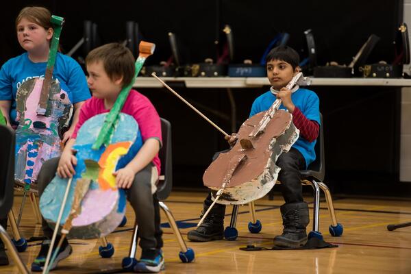 sistema students holding paper cellos