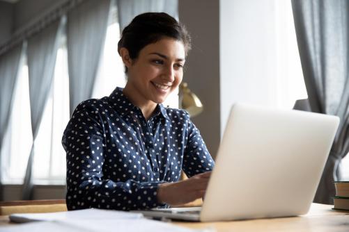 "student smiling while working on laptop"